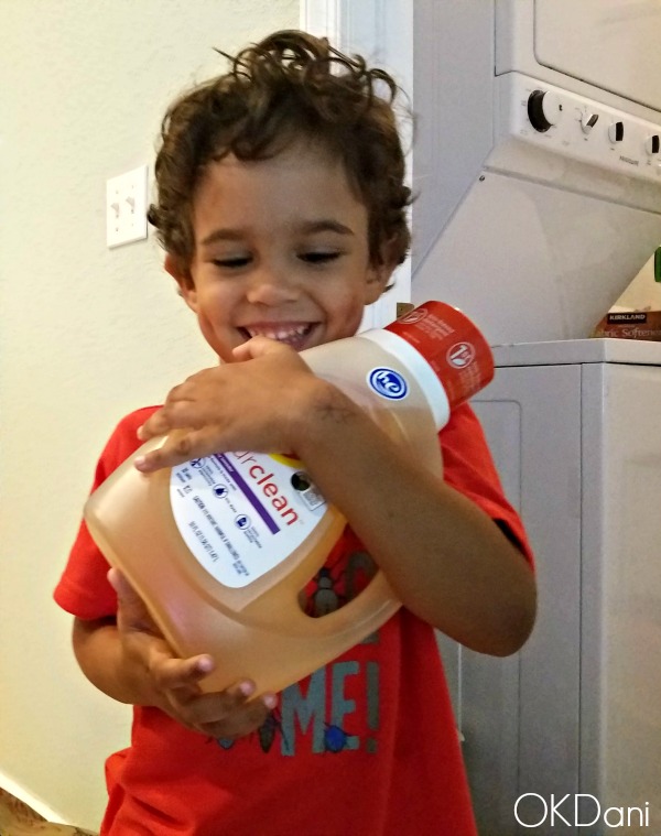 cute mixed toddler holding bottle of detergent with a smile